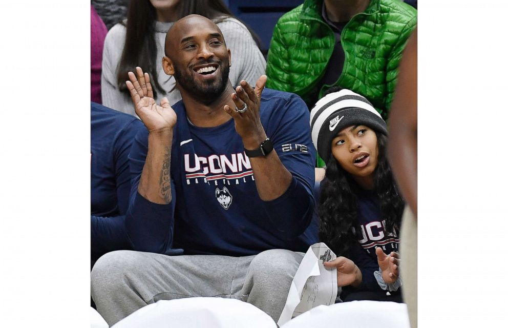 PHOTO: In this March 2, 2019, photo, Kobe Bryant and his daughter, Gianna, watch the first half of an NCAA college basketball game between Connecticut and Houston in Storrs, Conn. 