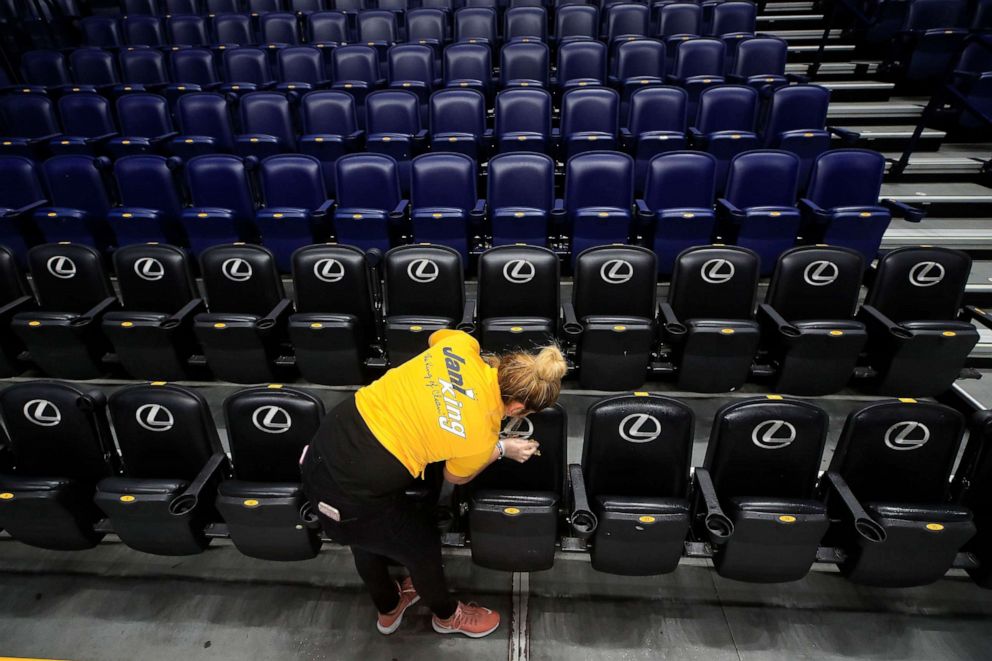 PHOTO: A worker cleans the seats after the announcement of the cancellation of the SEC Basketball Tournament due to the coronavirus at Bridgestone Arena, March 12, 2020, in Nashville, Tenn.