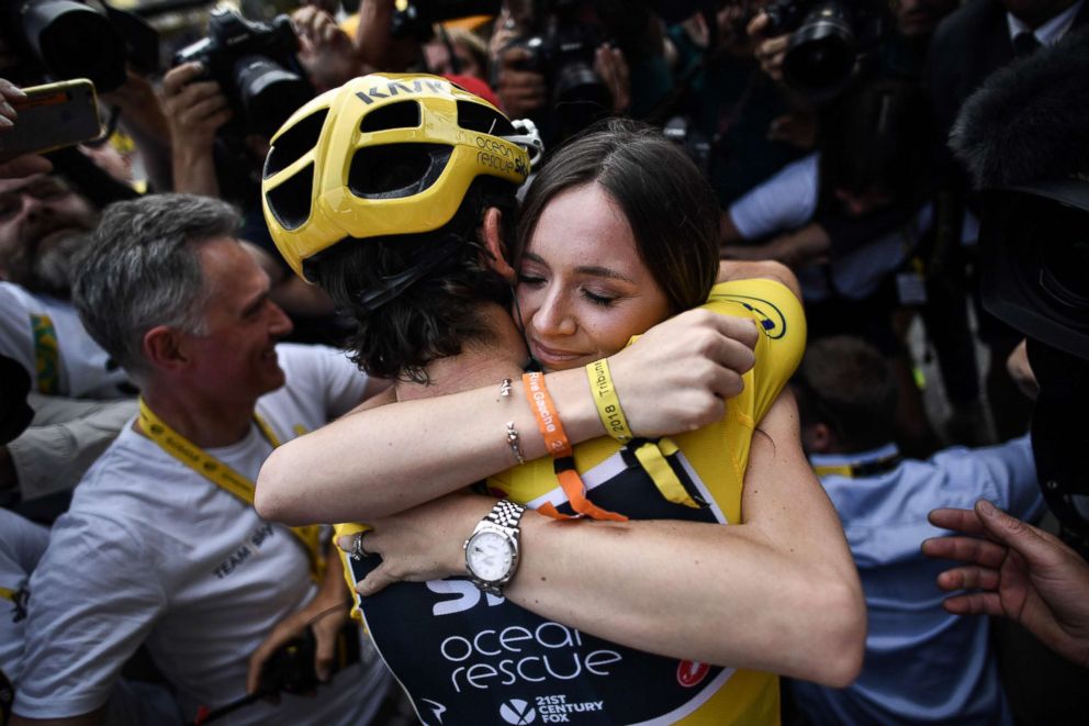 PHOTO: Tour de France winner Geraint Thomas (L) wearing the overall leader's yellow jersey hugs his wife Sarah-Ellen (R) as he celebrates after the 21st and last stage of the 105th edition of the Tour de France cycling race in  Paris, July 29, 2018. 