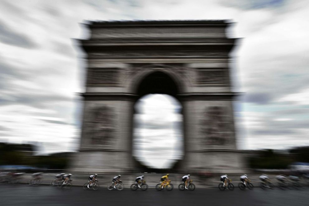 PHOTO: Great Britain's Geraint Thomas (C) wearing the overall leader's yellow jersey rides  past the Arc de triomphe monument during the Tour de France cycling race between Houilles and Paris Champs-Elysees, July 29, 2018. 