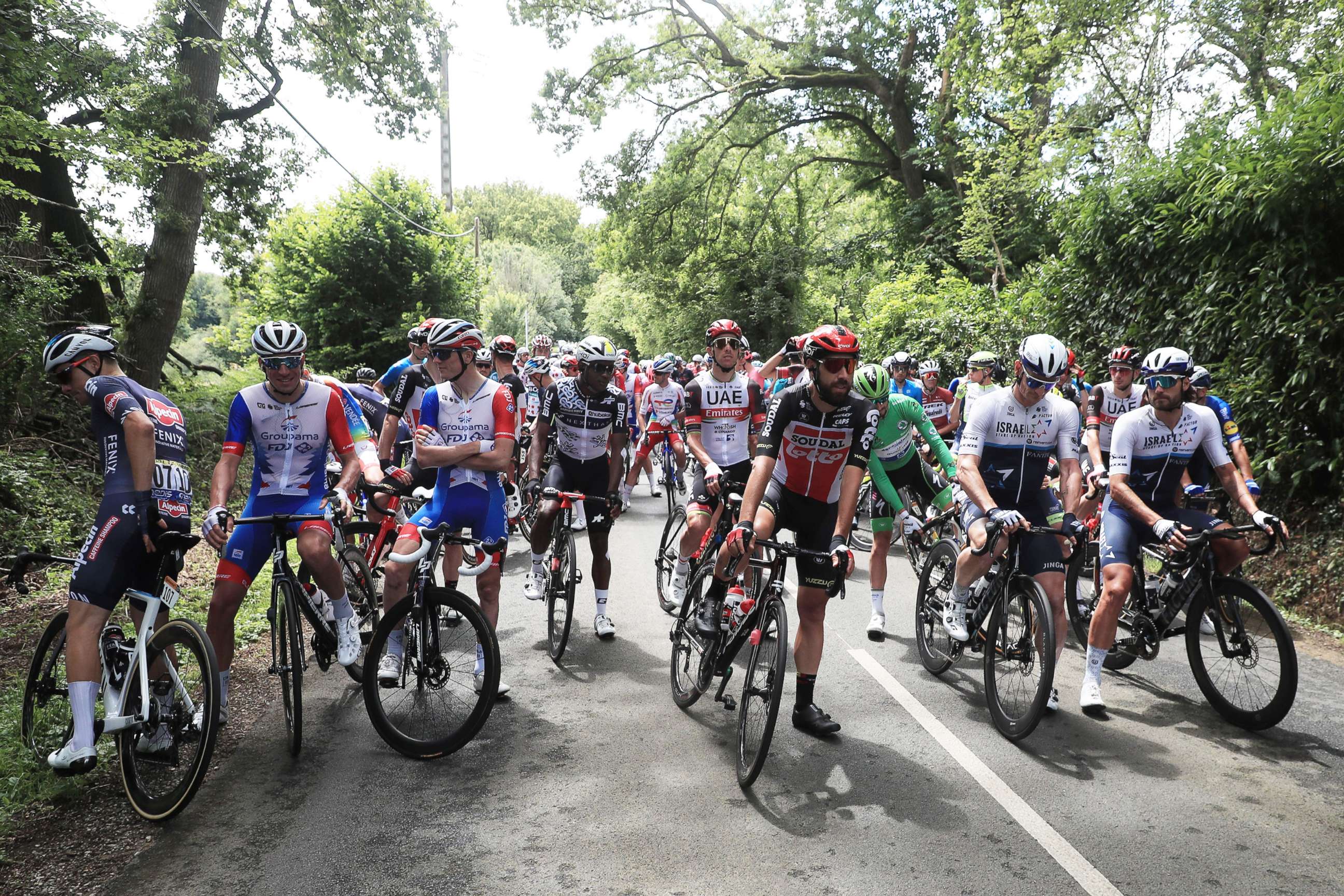 PHOTO: Belgian rider Thomas De Gendt of the Lotto Soudal team, center, and the peloton stop at kilometer zero for a minute in protest of the safety measures on this year's Tour de France, June 29, 2021.