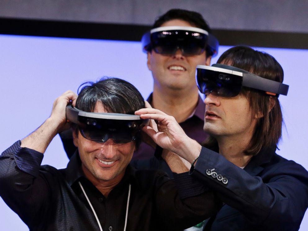 PHOTO: Microsofts Joe Belfiore (L) smiles as he tries on a Hololens device with colleagues Alex Kipman (R) and Terry Myerson following an event demonstrating new features of Windows 10 at the companys headquarters on Jan. 21, 2015, in Redmond, Wash.
