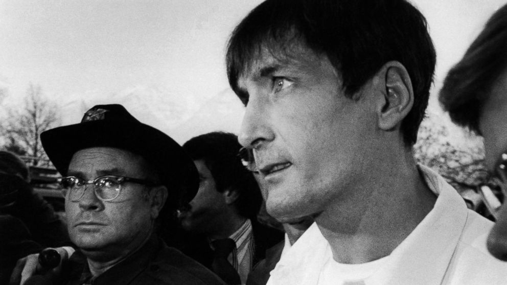 Gary Gilmore, wearing prison maximum security white uniform, faces barrage of newsmen and law enforcement officers on way to 4th District Court for new execution date in Provo, Utah, Dec. 3, 1976. (AP Photo)