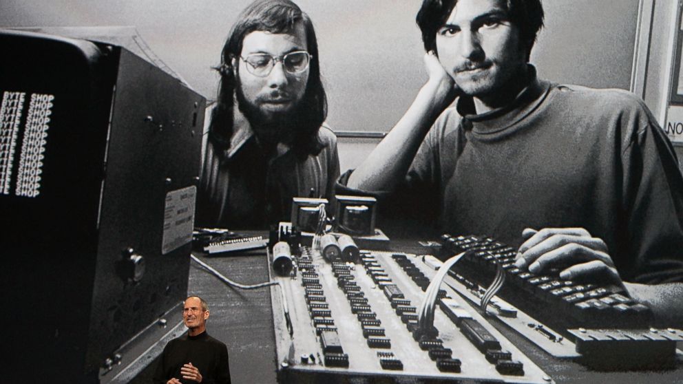 PHOTO: Steve Jobs, chief executive officer of Apple Inc., right, speaks in front of a file photograph of himself and Apple co-founder Steve Wozniak during the launch of the Apple iPad tablet in San Francisco, Calif., on Jan. 27, 2010. 