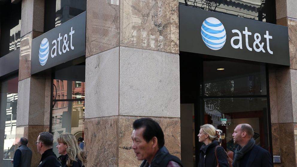 Pedestrians walk by an AT&T store in this Oct.  23, 2013, file photo in San Francisco, Calif. 
