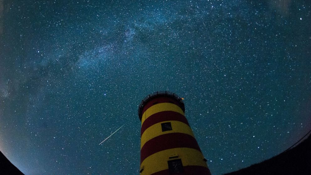 PHOTO: A falling star crosses the night sky behind a lighthouse is pictured during the peak in activity of the annual Perseids meteor shower on Aug. 13, 2015 in Pilsum, Germany. 
