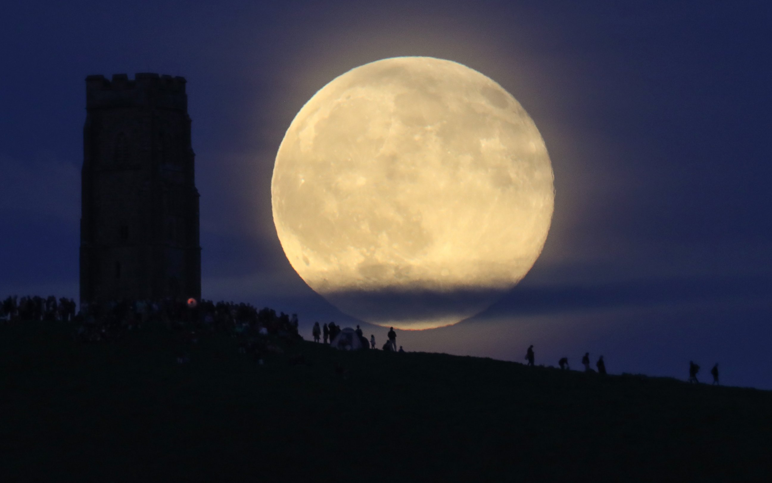 PHOTO: A full moon rises behind Glastonbury Tor as people gather to celebrate the summer solstice, June 20, 2016, in Somerset, England. 