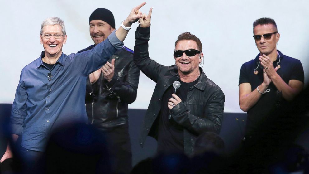 Apple CEO Tim Cook, left, greets the crowd with U2 during an Apple special event at the Flint Center for the Performing Arts, Sept. 9, 2014, in Cupertino, California.