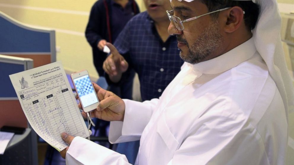 Cheif Arbiter Mahdi Abdulrahim examines at Gaioz Nigalidze's score sheet and phone.