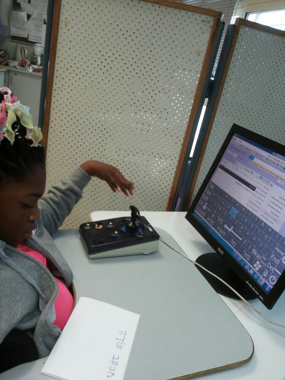 PHOTO: A young girl learns to use the Click2Speak on-screen keyboard with a joystick controller