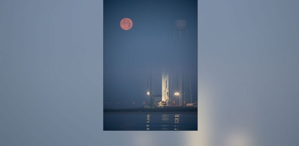 PHOTO: The full Moon sets in the fog behind the Orbital Sciences Corporation Antares rocket, with the Cygnus spacecraft onboard, Saturday, July 12, 2014, launch Pad-0A, NASA's Wallops Flight Facility in Virginia.