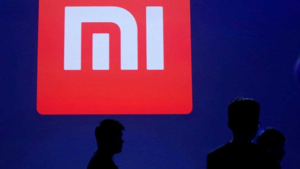 Attendants are silhouetted in front of Xiaomi's logo at a venue for the launch ceremony of Xiaomi's new smart phone Mi Max in Beijing, May 10, 2016.
