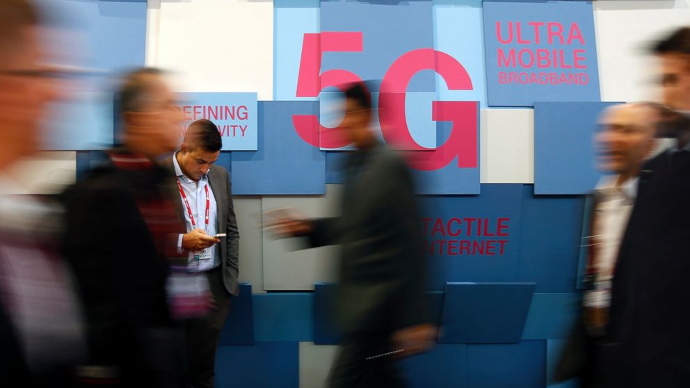 People walk past a 5G banner during the Mobile World Congress in Barcelona, Spain Feb. 23, 2016. 