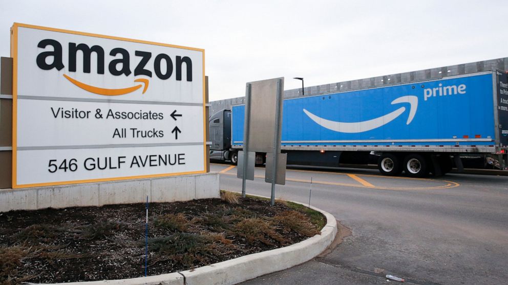 FILE - An Amazon Prime truck passes by a sign outside an Amazon fulfillment center on the Staten Island borough of New York, on March 19, 2020. Amazon is raising charges on third-party sellers again — this time adding a holiday fee for merchants who 