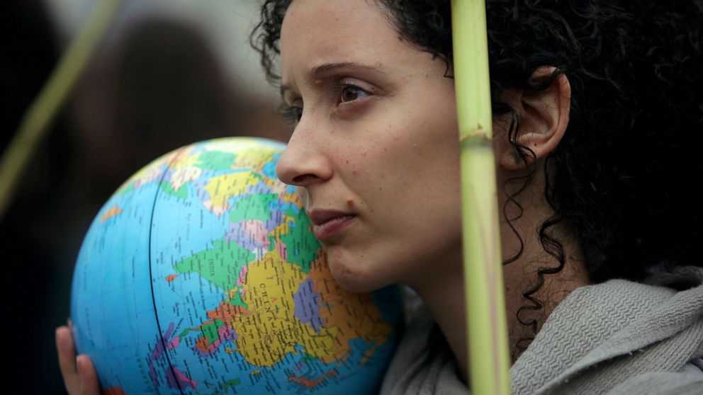 FILE- In this Nov. 29, 2019, file photo, a demonstrator holds a terrestrial globe in Lisbon during a worldwide protest demanding action on climate change. The European Union's top court definitively rejected an effort by a Scandinavian youth group an