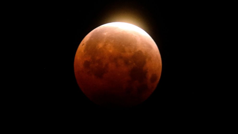 FILE - Light shines from a total lunar eclipse over Santa Monica Beach in Santa Monica, Calif., Wednesday, May 26, 2021. A total lunar eclipse will grace the night skies this weekend, providing longer than usual thrills for stargazers across North an
