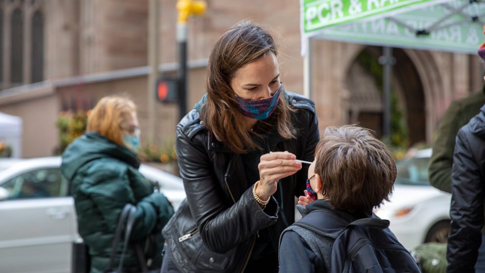 FILE - Katie Lucey administers a COVID-19 test on her son Maguire at a PCR and Rapid Antigen COVID-19 coronavirus test pop up on Wall Street in New York on Thursday, Dec. 16, 2021. U.S. health officials are endorsing ‘test-to-stay’ policies that will
