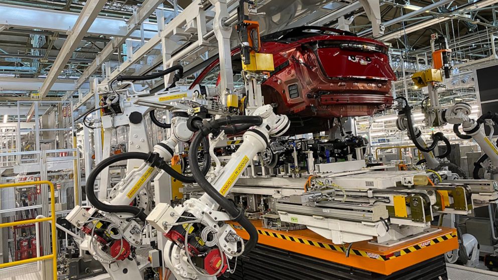 Robotic arms put in the electric vehicle powertrain into the Ariya model in the assembly line at Nissan's Tochigi plant in Kaminokawa town, Tochigi prefecture, Japan, Friday, Oct. 8, 2021. Nissan’s “intelligent factory” hardly has any human workers. 