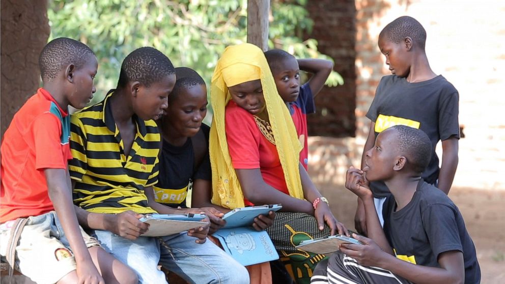 In this undated photo provided by XPRIZE, children in a village in the Tanga region of Tanzania gather to learn from tablets using open-sourced software that would easily be downloaded by illiterate children to teach themselves to read. That's what n