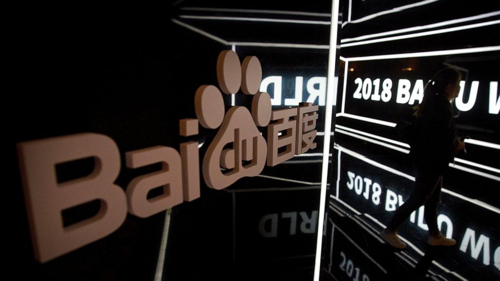 FILE - In this Nov. 1, 2018, file photo, an attendee walks past a display at the 2018 Baidu World conference in Beijing. China’s market regulator said Friday, March 12, 2021, that it fined 12 companies, including games company Tencent Holdings and Ch