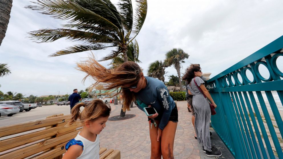 Kristen Davis watches the high surf from a boardwalk overlooking the Atlantic Ocean with her daughter Addie Davis, 4, as winds from Hurricane Dorian blow the fronds of a palm tree in Vero Beach, Fla., Monday, Sept. 2, 2019. (AP Photo/Gerald Herbert)