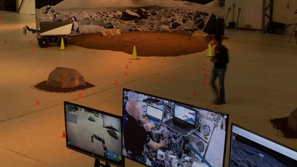 FILE - Astronaut Luca Parmitano of Italy, seen on screen, flashes a thumbs up, as he controls the Space Rover, rear, which successfully picked up a rock during a training exercise of the European Space Agency, ESA, in Katwijk, near The Hague, Netherl