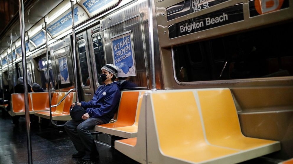 A commuter wears a face mask while riding the a nearly empty subway car into Brooklyn, Thursday, March 12, 2020, in New York. New York City Mayor Bill de Blasio said Thursday he will announce new restrictions on gatherings to halt the spread of the n