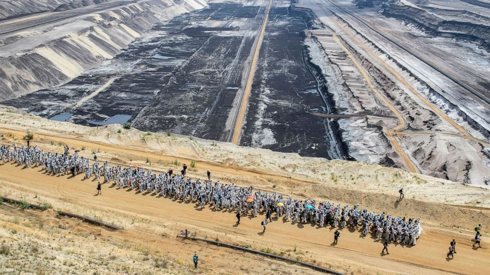 Numerous environmental activists walk on a roadway on the site of the Garzweiler open-cast mine in Garzweiler, Germany, Saturday, June 22, 2019. The protests for more climate protection in the Rhineland continue. (Marcel Kusch/dpa via AP)