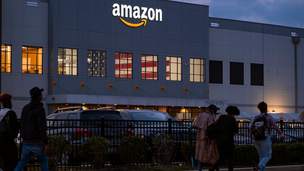 FILE - People arrive for work at the Amazon distribution center in the Staten Island borough of New York, on Oct. 25, 2021. A federal judge has ordered Amazon to stop retaliating against employees engaged in workplace activism, issuing a mixed ruling