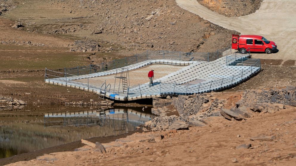 FILE - A man walks on a floating swimming pool resting on dry ground of the water depleted Zezere River due to drought near, Pampilhosa da Serra in central Portugal, Thursday, Feb. 17, 2022. Almost the whole of Portugal was in severe drought at the e