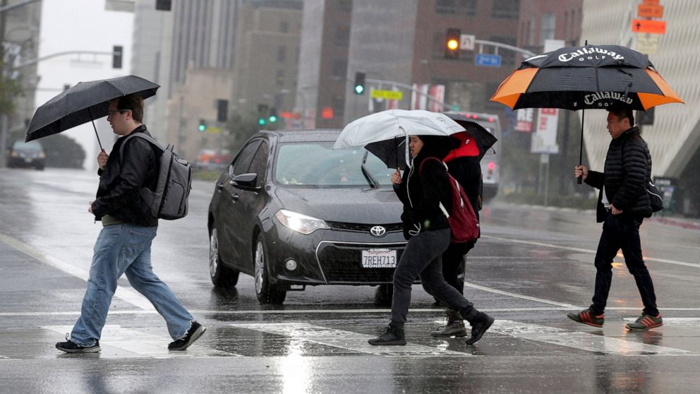 FILE - In this Monday, Feb. 6, 2017 file photo, pedestrians cross a rainy street in downtown Los Angeles. According to a study released in April 2019 in the Bulletin of the American Meteorological Society, even light rain significantly increases the 