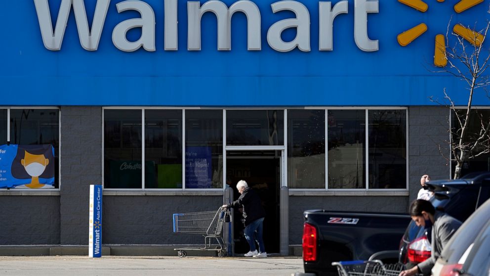 FILE - In this Nov. 5, 2020 file photo, a woman pushes a shopping cart to enter a Walmart in Rolling Meadows, Ill. Walmart is unveiling an app for its store workers' phones that allows them to do a variety of tasks from digitally clocking into work t