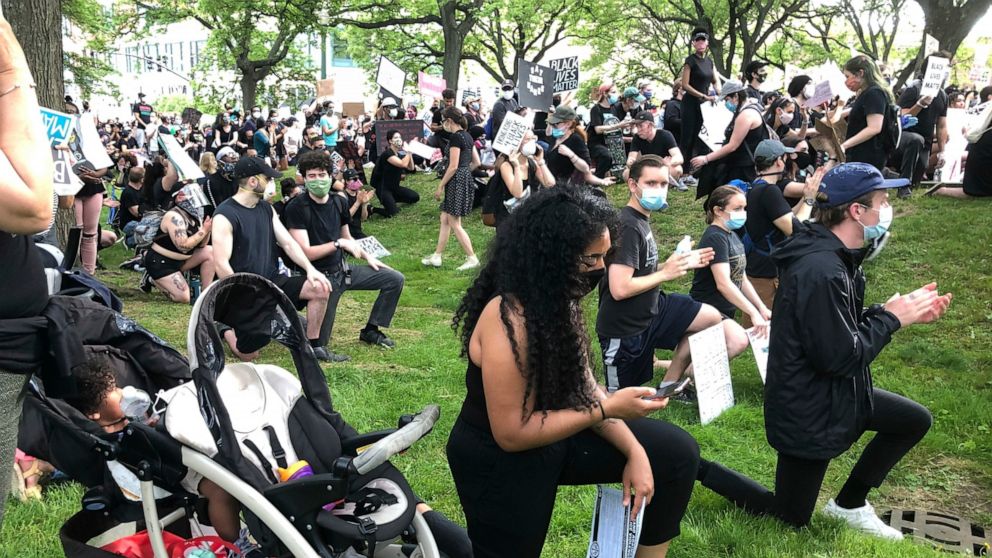 Anjel Newmann, 32, kneels while scanning her phone during a peaceful rally in Providence, R.I. on Friday, June 5. Newmann said she’s mostly using Instagram and Facebook to organize protests while people younger than her are using Snapchat. (AP Photo/