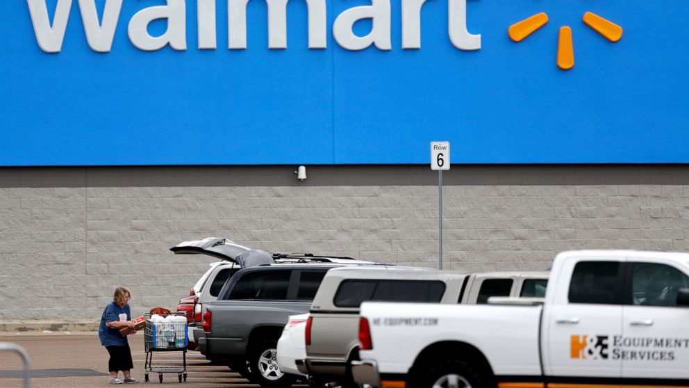 FILE - In this March 31, 2020 file photo, a woman pulls groceries from a cart to her vehicle outside of a Walmart store in Pearl, Miss. Walmart is teaming with the General Motors' Cruise autonomous vehicle unit to test automated package delivery in A