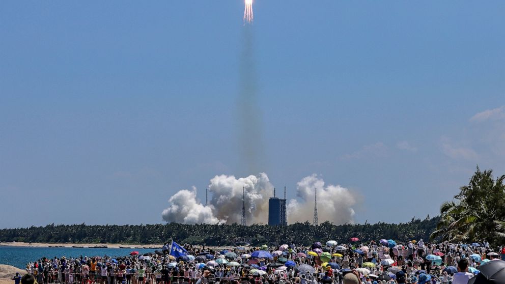 FILE - In this photo released by Xinhua News Agency, people gather at the beach side as they watch the Long March 5B Y3 carrier rocket, carrying Wentian lab module, lift off from the Wenchang Space Launch Center in Wenchang in southern China's Hainan