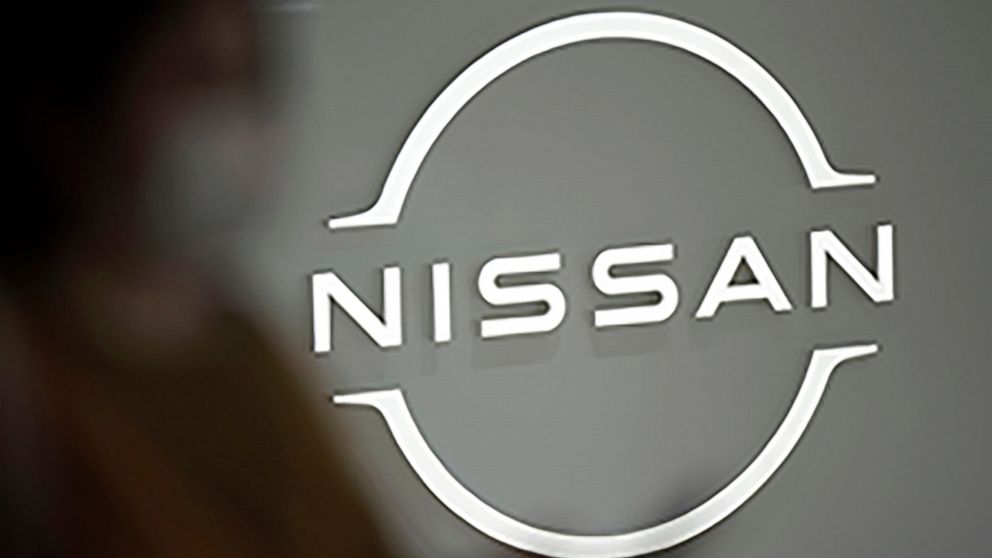 FILE - A visitor walks near a Nissan logo at Nissan headquarters on May 12, 2022, in Yokohama near Tokyo. Nissan is considering adding a new auto plant in the U.S. to keep up with growing demand for electric vehicles, a top executive at the Japanese 