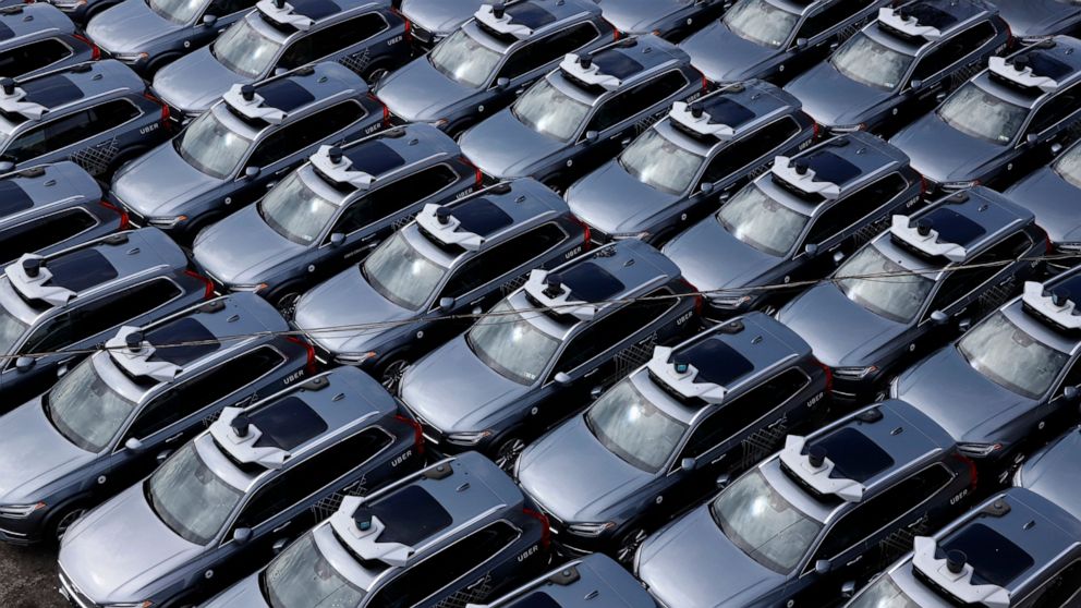 File-This March 20, 2020, file photo shows a parking lot full of Uber self-driving Volvos in Pittsburgh. Uber is selling off its autonomous vehicles development arm to Aurora as the ride-hailing company slims down after its revenues were pummeled by 