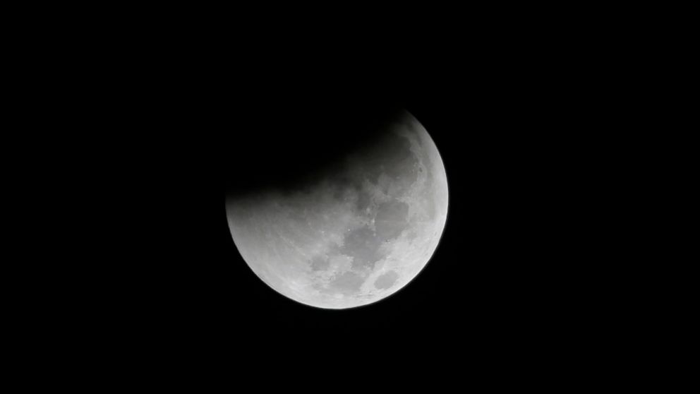 FILE - In this Saturday Aug. 28, 2018 file photo, Earth starts to cast its shadow on the moon during a complete lunar eclipse seen from Jakarta, Indonesia. Starting Sunday evening, Jan. 20, 2019, all of North and South America will be able to see the