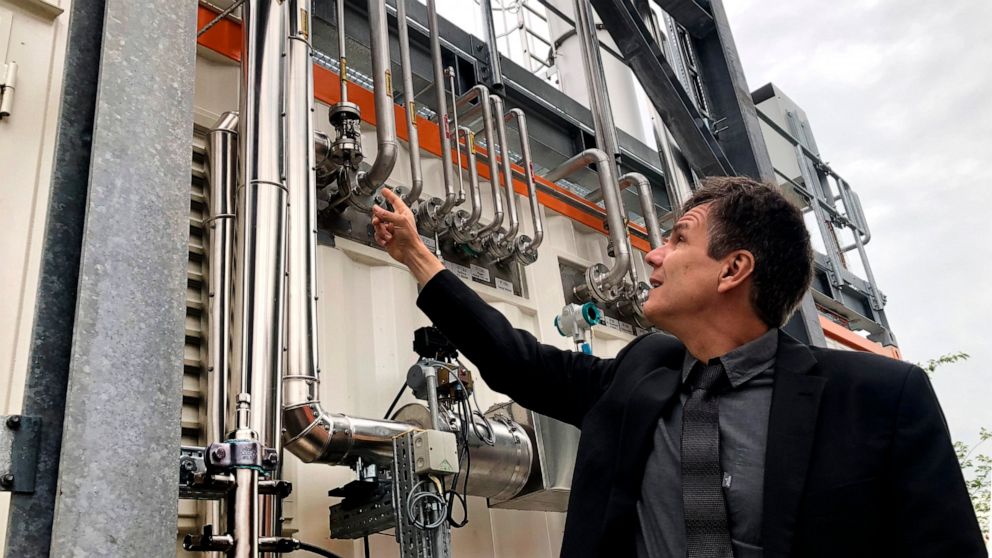 Dietrich Brockhagen, Executive Director of Atmosfair, points on pipes of the system that brings hydrogen and carbon into the facility that mix them and produce e-fuel at the 'Atmosfair' synthetic kerosene plant in Werlte, Germany, Monday, Oct. 4, 202