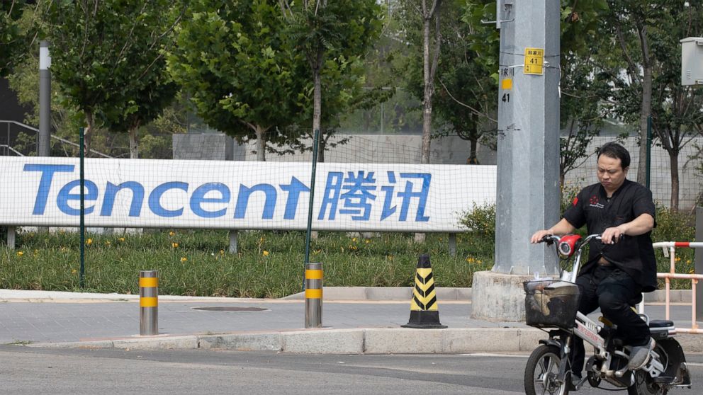 FILE - In this Aug. 7, 2020, file photo, a man rides past the Tencent headquarters in Beijing, China. Chinese authorities summoned 11 companies including Alibaba and Tencent for talks regarding the security of voice technology, as Beijing steps up sc