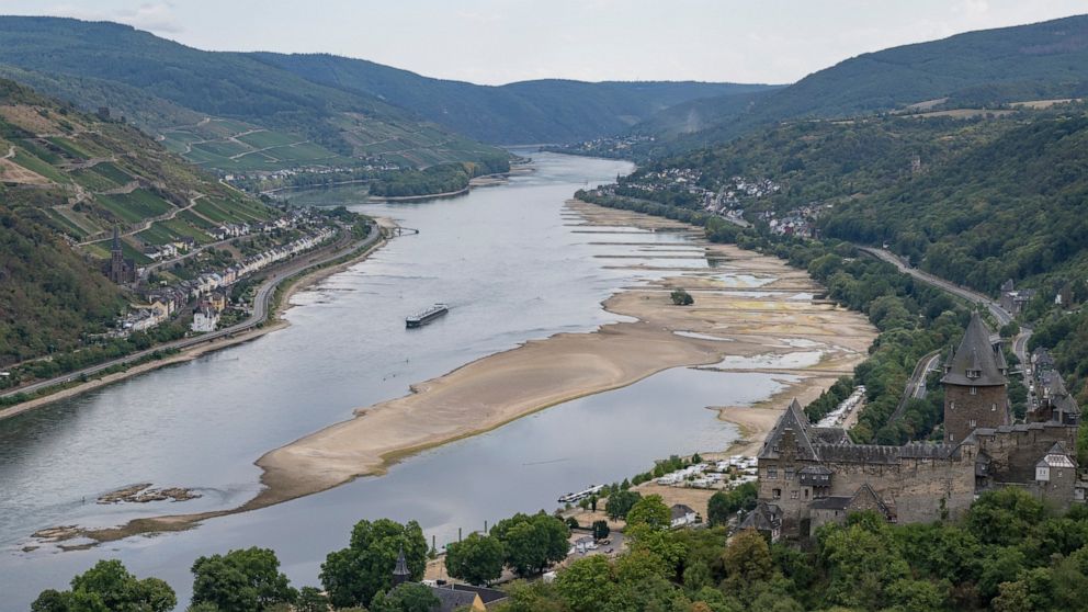 A barge passes exposed rocks and sandbanks on the river Rhine in Bacharach, Germany, Monday, Aug. 15, 2022. After weeks of drought, the water levels of the Rhine have reached historic lows. If the water levels continue to fall, shipping is in danger 