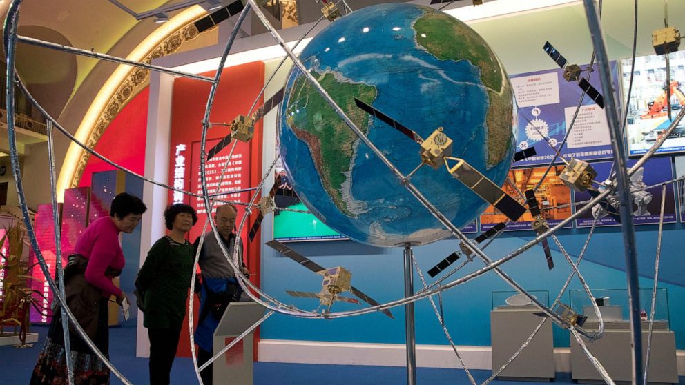 FILE - In this Oct. 19, 2017, file photo, visitors look at a display of satellite technologies at an exhibition highlighting China's achievements under five years of President Xi Jinping's leadership at the Beijing Exhibition Hall in Beijing. China o