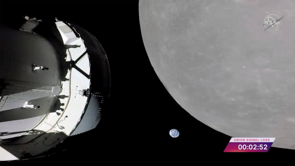 This screengrab from NASA TV shows NASA's Orion capsule, left, nearing the moon, right, Monday, Nov. 21, 2022. At center is earth. (NASA via AP)
