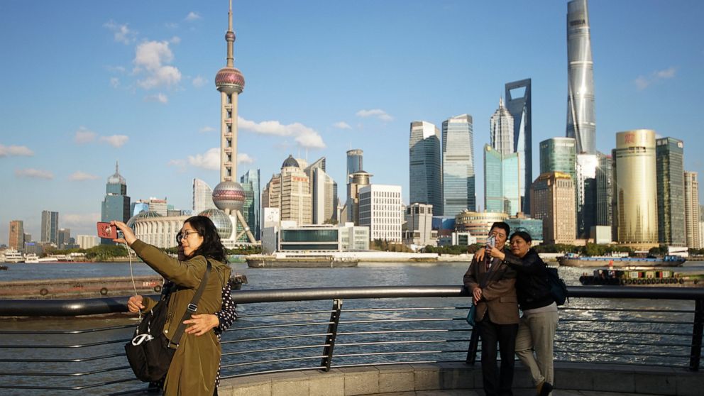 FILE - In this Nov. 12, 2020 file photo, people take selfies of the Pudong skyline as they stand on the Bund in Shanghai, China. A new study finds that cleaner air from the pandemic lockdown warmed the planet a bit in 2020, especially in places such 