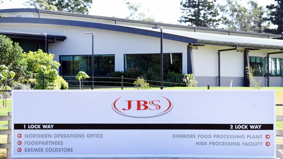 In this May 12, 2020, photo, the company logo sign sits at the entrance to the JBS Australia's Dinmore meatworks facility, west of Brisbane. Thousands of Australian meat workers had no work for a second day on Tuesday, June 1, 2021, after a cyberatta