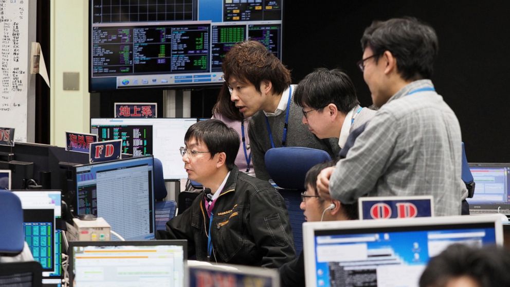 FILE - In this Feb. 21, 2019, file photo provided by the Japan Aerospace Exploration Agency JAXA, staff of the Hayabusa2 Project watch monitors for a safety check at the control room of the JAXA Institute of Space and Astronautical Science in Sagamih