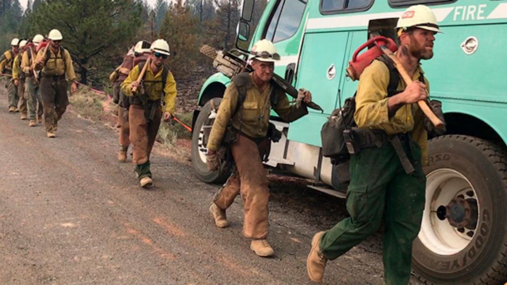 In this photo provided by the Bootleg Fire Incident Command, a handcrew walks to engage the Bootleg Fire in southern Oregon on Monday, July 19, 2021. The Oregon fire has ravaged the southern part of the state and has been expanding by up to 4 miles (