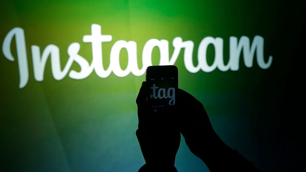 FILE - In this June 20, 2013 file photo, a journalist makes a video of the Instagram logo using the new video feature at Facebook headquarters in Menlo Park, Calif. British regulators said Friday, Oct. 16, 2020 that Instagram will clamp down on “hidd