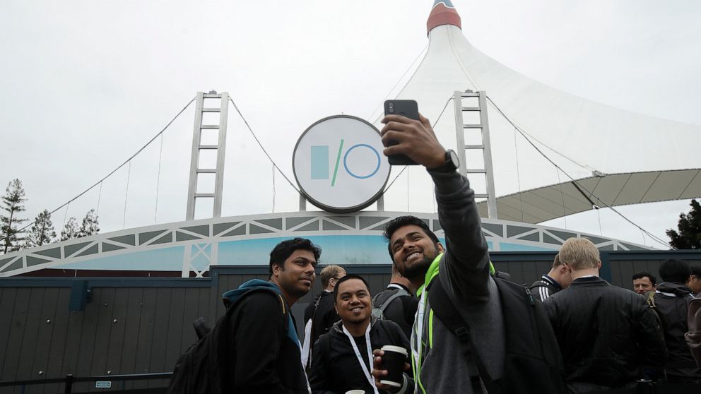 A group of attendees take photos while waiting in line for the keynote address of the Google I/O conference in Mountain View, Calif., Tuesday, May 7, 2019. (AP Photo/Jeff Chiu)