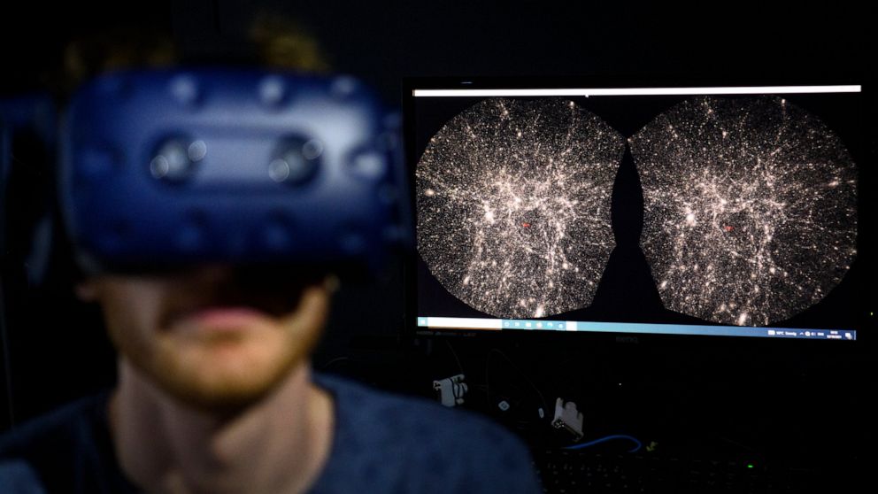 FILE - In this Oct. 12, 2021 file photo, Hadrien Gurnel, software engineer EPFL's Laboratory for Experimental Museology (eM+) explores with a virtual reality helmet the most detailed 3D map of the universe with the virtual reality software VIRUP, Vir
